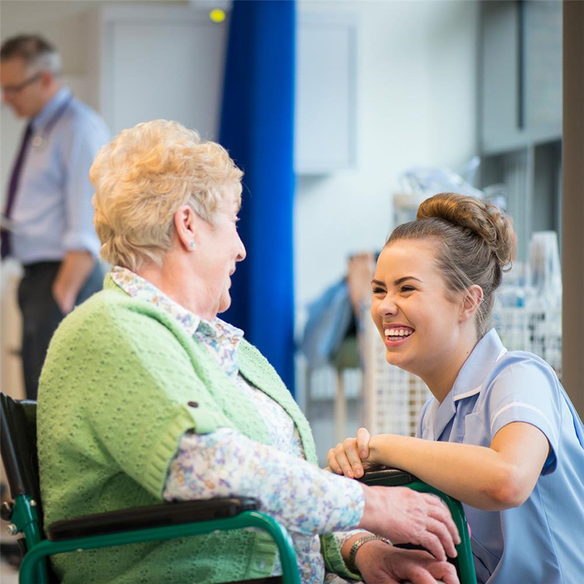 Hospitantin und Frau im Rollstuhl lachen